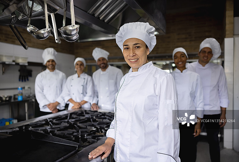 快乐的厨师和她的厨师团队在餐厅的厨房图片素材