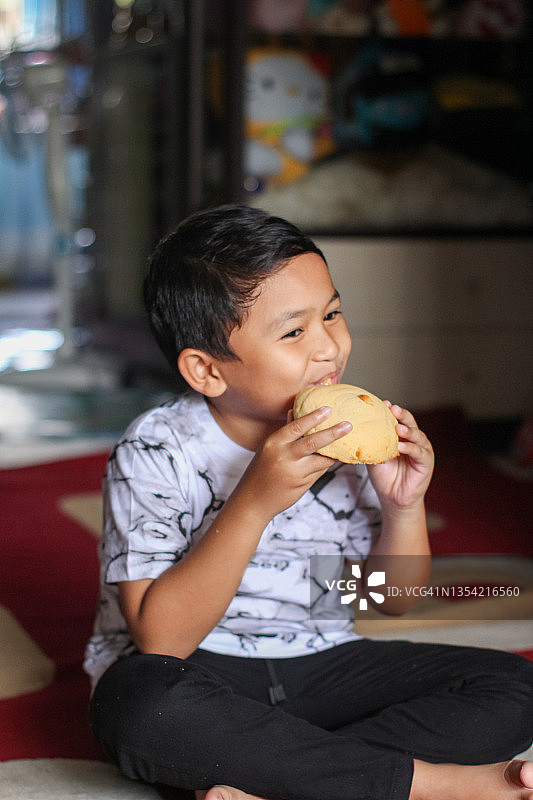 男孩坐在家里吃面包图片素材