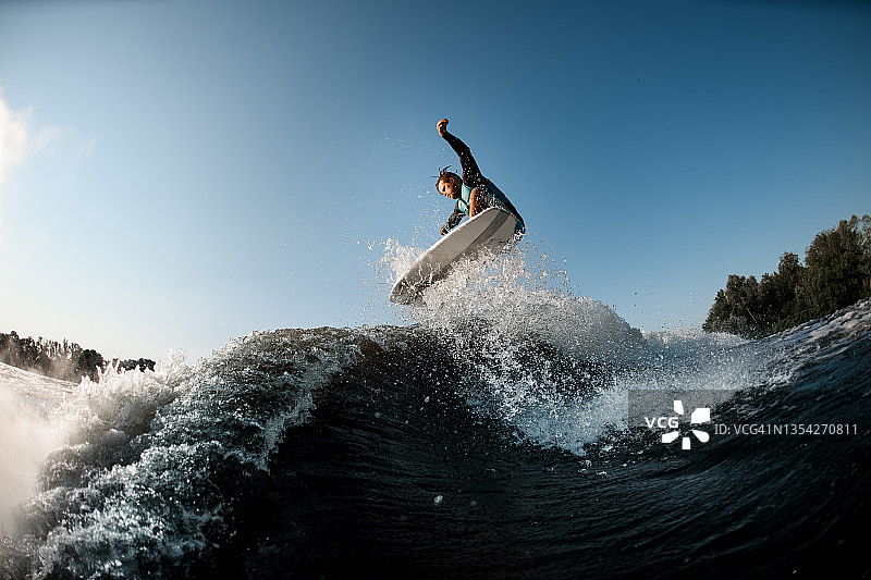 波浪冲浪者在蓝天的背景下积极跳跃图片素材