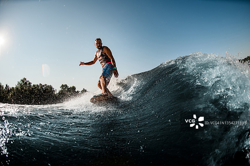 夏天的时候，男人骑在溅起水花的波浪上图片素材