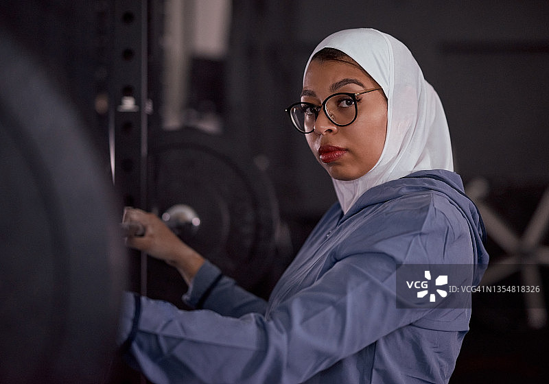 一个迷人的穆斯林女子独自站在健身房准备锻炼图片素材