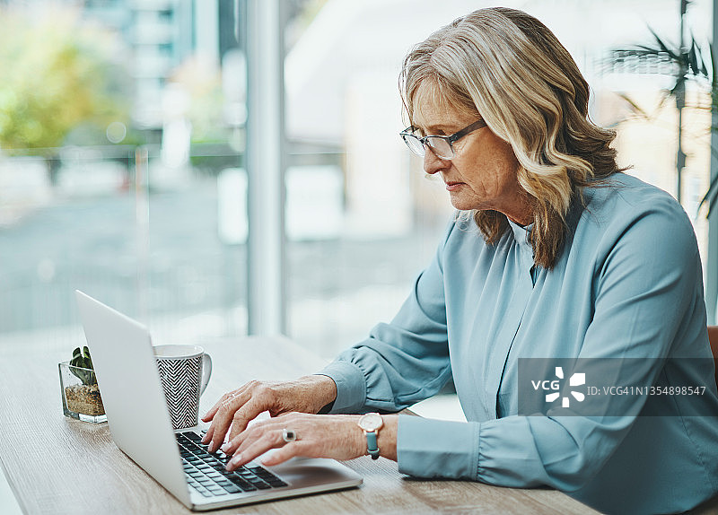 一个成熟的女商人在一个现代化的办公室里使用笔记本电脑图片素材