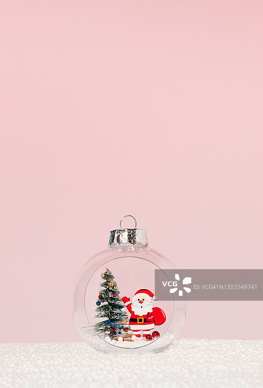 圣诞树和圣诞老人里面的圣诞装饰物在淡粉色的背景上。最小的新年概念。创造性的冬天的想法。图片素材