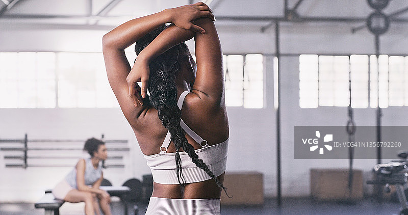 一个无法辨认的年轻健康女性在健身房锻炼前做热身伸展运动的后视镜图片素材
