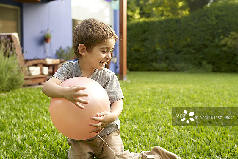 侧面的内容孩子站在彩色气球在草地上，看着一边享受阳光的日子图片素材
