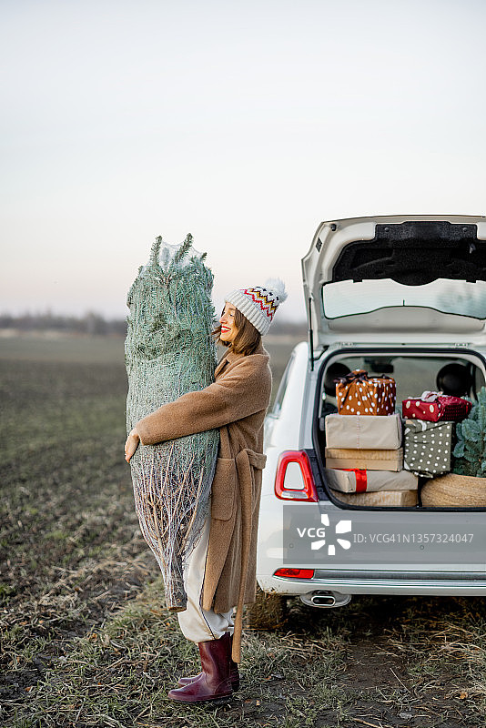 女人走在圣诞树附近的汽车上自然图片素材