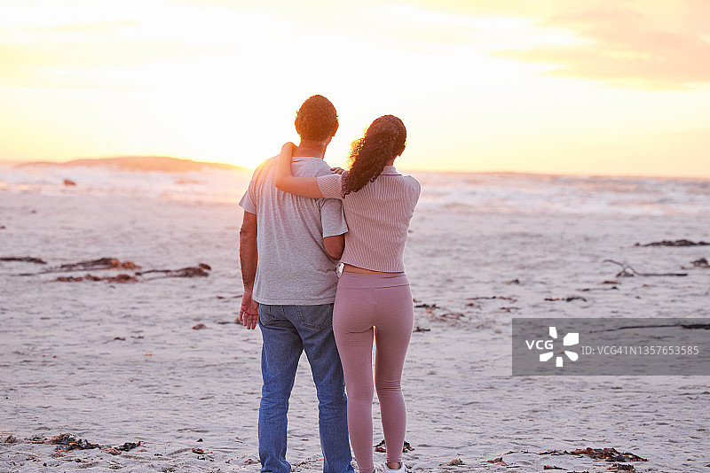 一个无法辨认的女人和她的父亲站在海滩上看日落图片素材