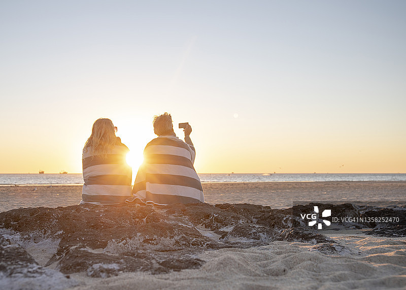成熟的夫妇在日出时在沙滩上放松图片素材