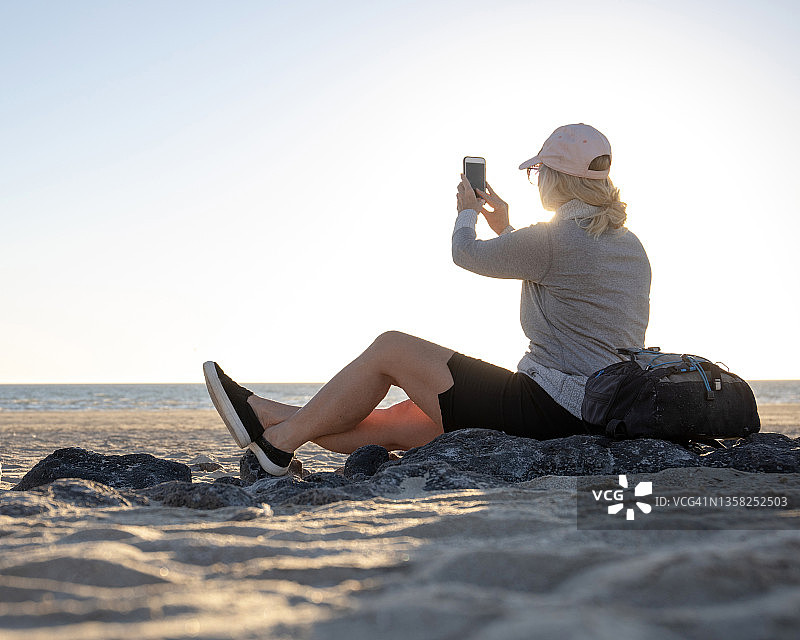 日出时，一名女子在沙滩上放松图片素材