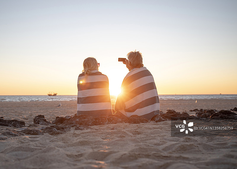 成熟的夫妇在日出时在沙滩上放松图片素材
