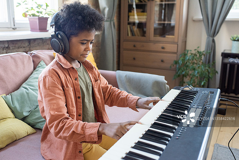 快乐勤奋的男孩按下钢琴键盘上的键图片素材