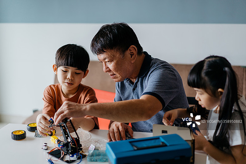 爷爷和孙子在家里制作机器人玩具图片素材