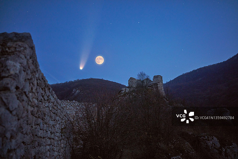 满月，彗星和星星在中世纪堡垒和山区景观。图片素材