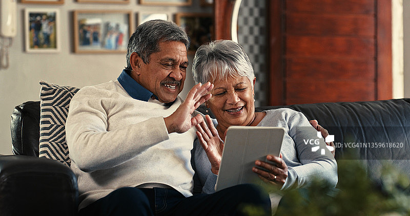这张照片拍摄的是一对老夫妇在家里的沙发上用数码平板电脑进行视频通话图片素材