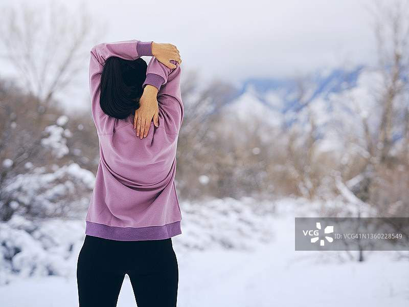 一个女人在冬季跑步前伸展身体图片素材