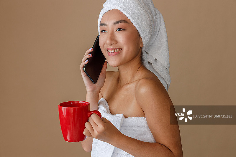 快乐的亚洲妇女在淋浴后打电话图片素材