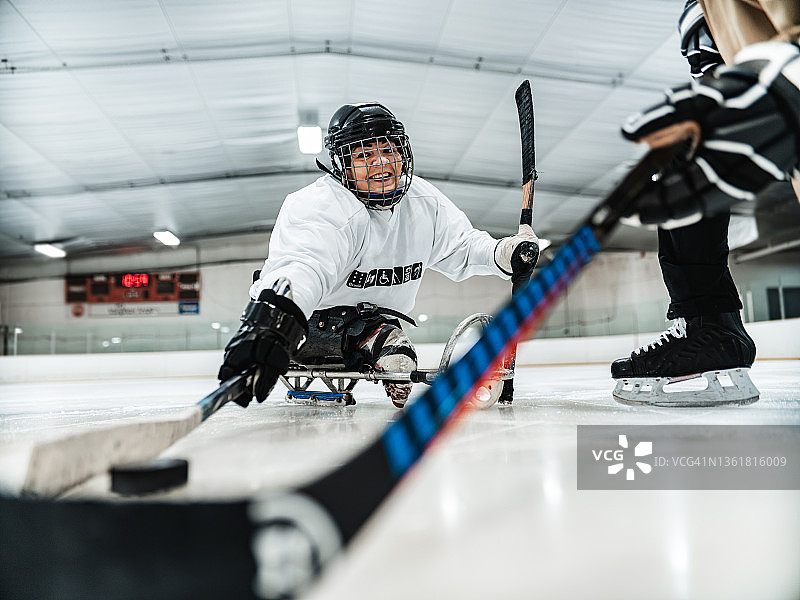 成熟的残疾人拉丁妇女和她的教练练习雪橇曲棍球图片素材