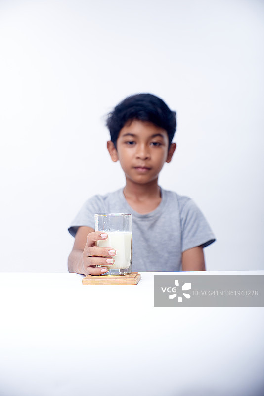 一个亚洲男孩拿着一杯健康的新鲜牛奶图片素材