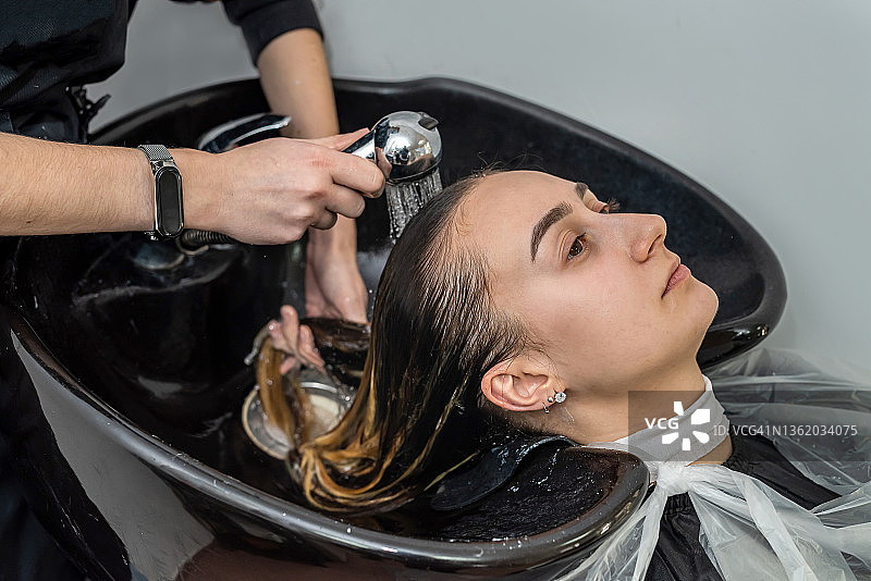 顶视图作为一个大师色彩洗头一个年轻女孩的头在美容院。图片素材