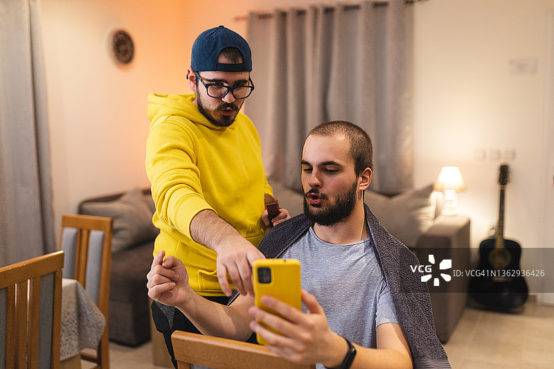 由于新冠肺炎疫情，年轻人在家理发之前，在智能手机上向理发师展示自己想要的发型图片素材