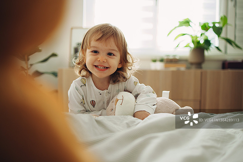 一个快乐的小女孩早上在卧室里玩耍的肖像图片素材