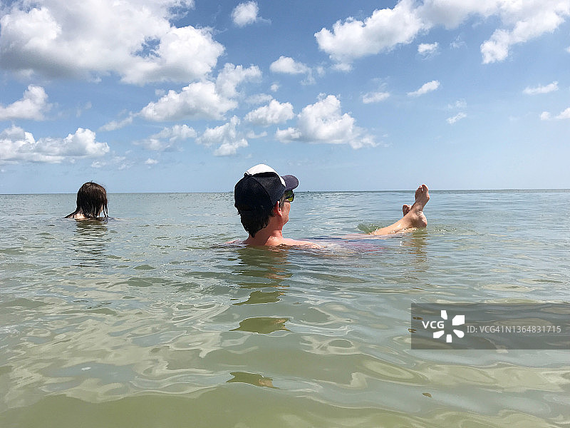 在一个美好的日子里，十几岁的女儿和她的爸爸在海上漂浮图片素材
