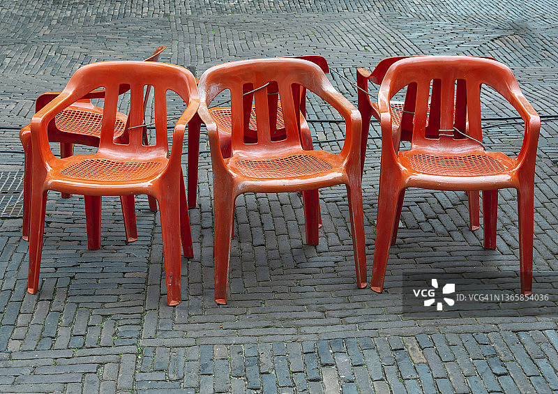 六把橙色的户外椅子，用电缆绑在一起图片素材