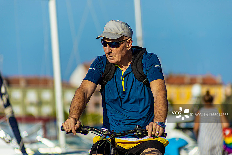 重要的白人年长男子，骑自行车在码头，在阳光明媚的夏日图片素材