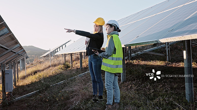 在太阳能发电厂工作的女性工程师。团队合作。可再生能源系统。太阳能城市。图片素材