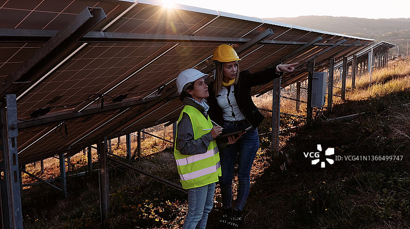在太阳能发电厂工作的女性工程师。团队合作。可再生能源系统。太阳能城市。图片素材