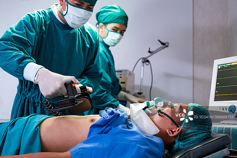 在手术室内进行医学手术时，医生用除颤器对昏迷低心率的病人进行胸腔抽吸以挽救生命。紧急援助,心肺复苏术。图片素材