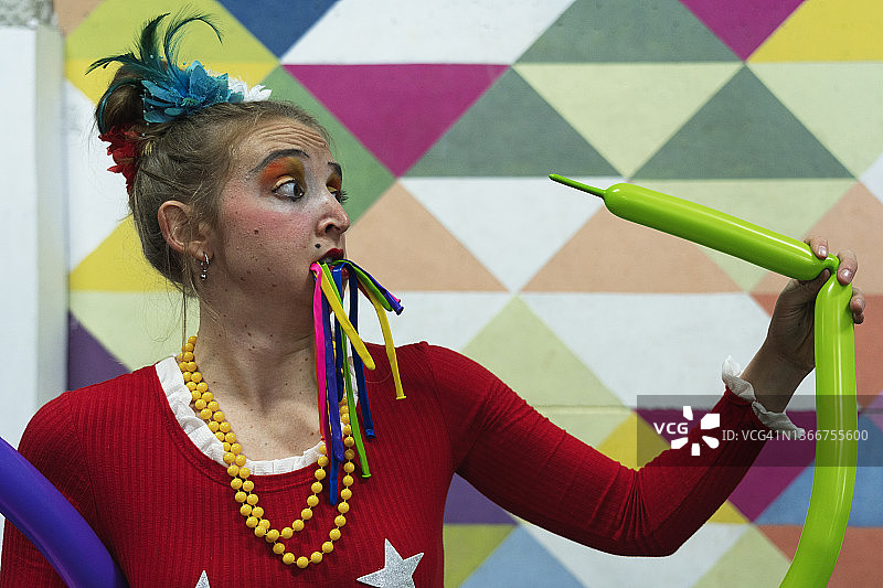 小丑女孩和马戏演员在表演前进行热身练习。喜剧演员玩气球图片素材