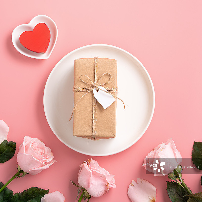 情人节礼物和餐设计概念背景与粉红色的玫瑰花在粉红色的背景。图片素材