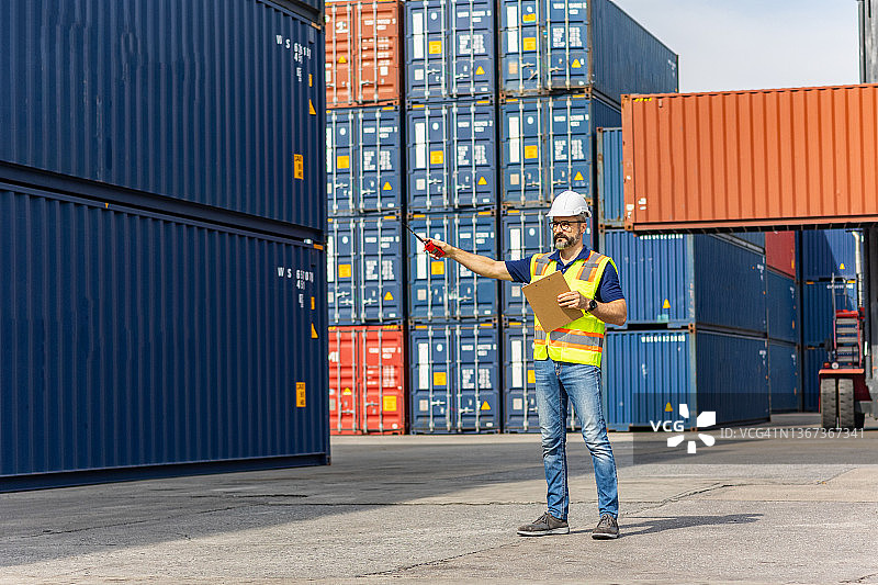 在集装箱仓库，工头工人控制从国际进出口行业的货轮上装载集装箱。图片素材