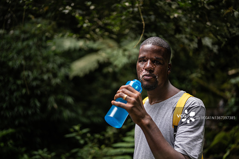 一名中年男子在森林里喝水的肖像图片素材