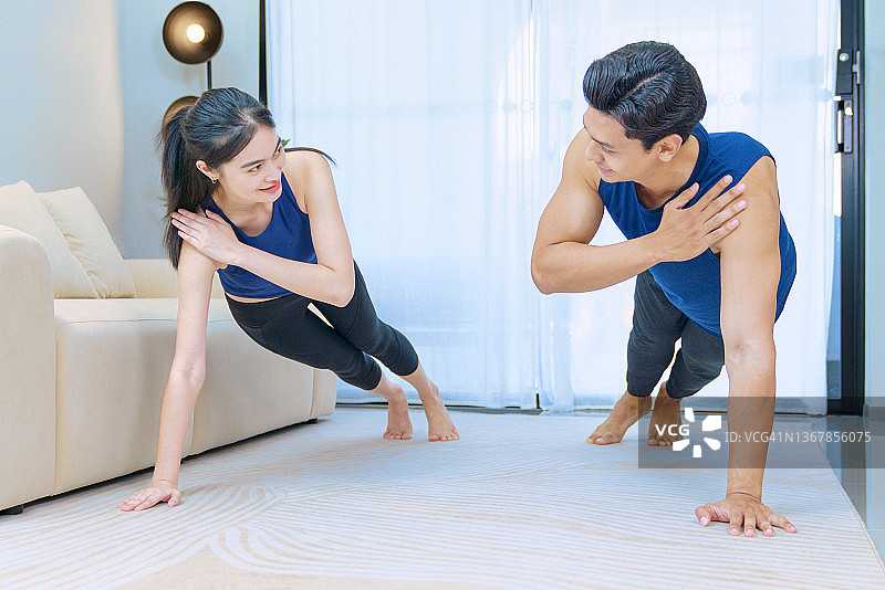 一对快乐的年轻夫妇在隔离室做瑜伽。伸展运动。锻炼。强壮美丽的运动健身夫妇穿着运动服在家图片素材