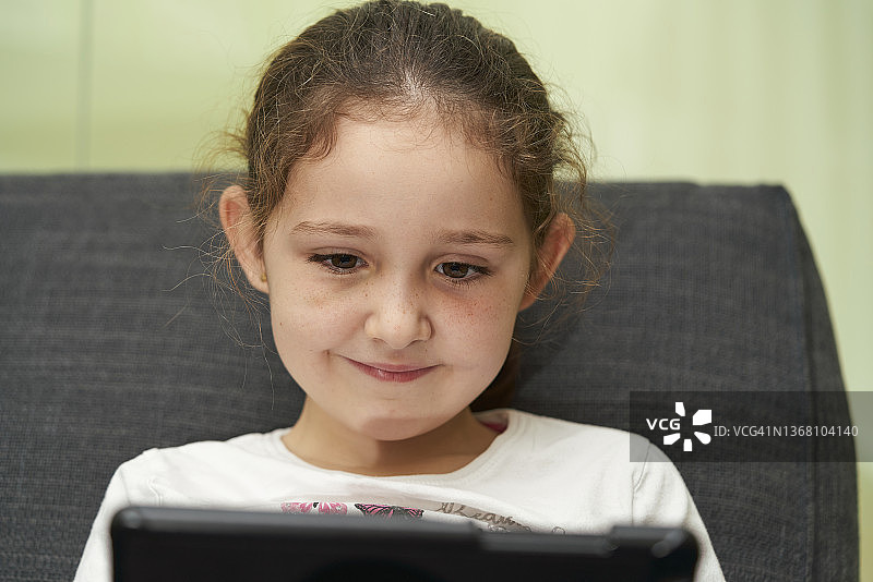 小女孩在家里用数码平板电脑。图片素材