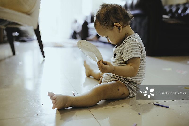 可爱的宝宝在客厅里玩玩具和看书图片素材