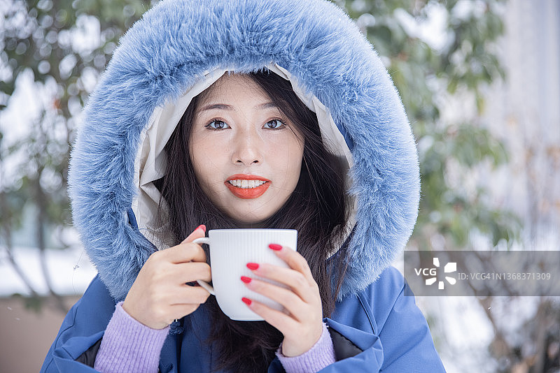 冬天，年轻的女子端着一杯热咖啡图片素材
