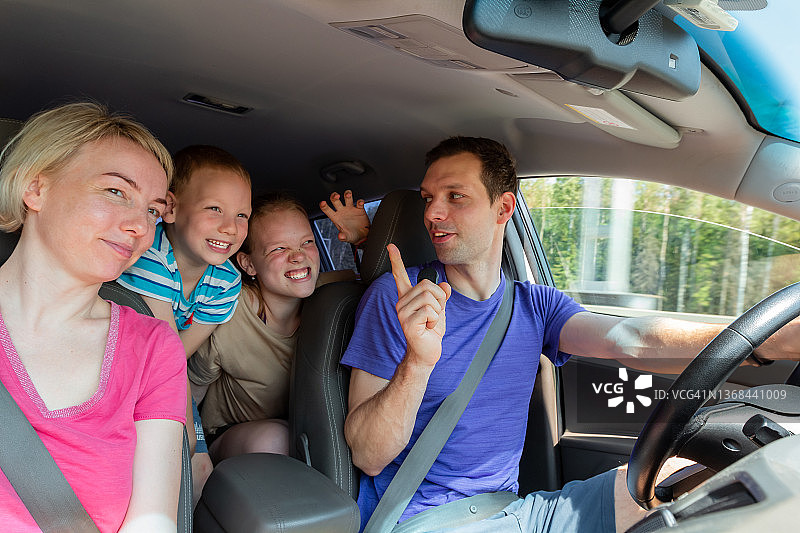 幸福快乐的父母和他们的儿子和女儿在车里玩暑假和公路旅行。周末全家一起在大自然中活动。快乐在一起图片素材