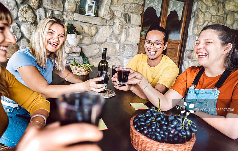 快乐的人们在农家天井畅饮-与年轻朋友在小木屋共享丰收的生活理念-在户外独特体验品尝红酒-温暖生动的滤镜图片素材