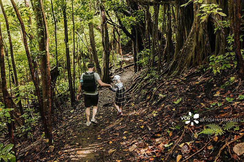 在夏威夷森林徒步旅行时，父亲帮助女儿下山图片素材