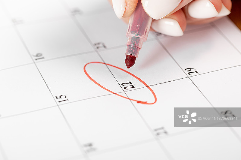 女性手用红笔在日历上圈出日期、截止日期的概念图片素材
