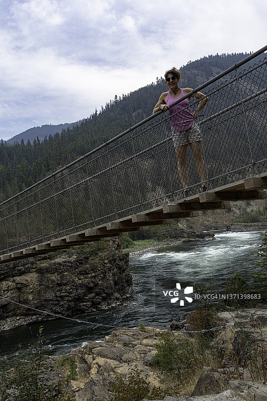 蒙大拿州库特奈瀑布悬索桥上，一名女子微笑着站在桥顶图片素材