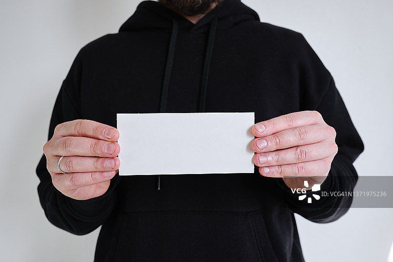 白色的空牌在一个男人的手中在黑色的背景上。放置文字和广告。名片图片素材