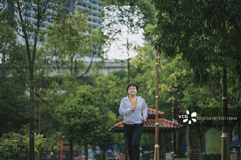 亚洲华人中年妇女与白色运动服跑步微笑看向远处的公园图片素材