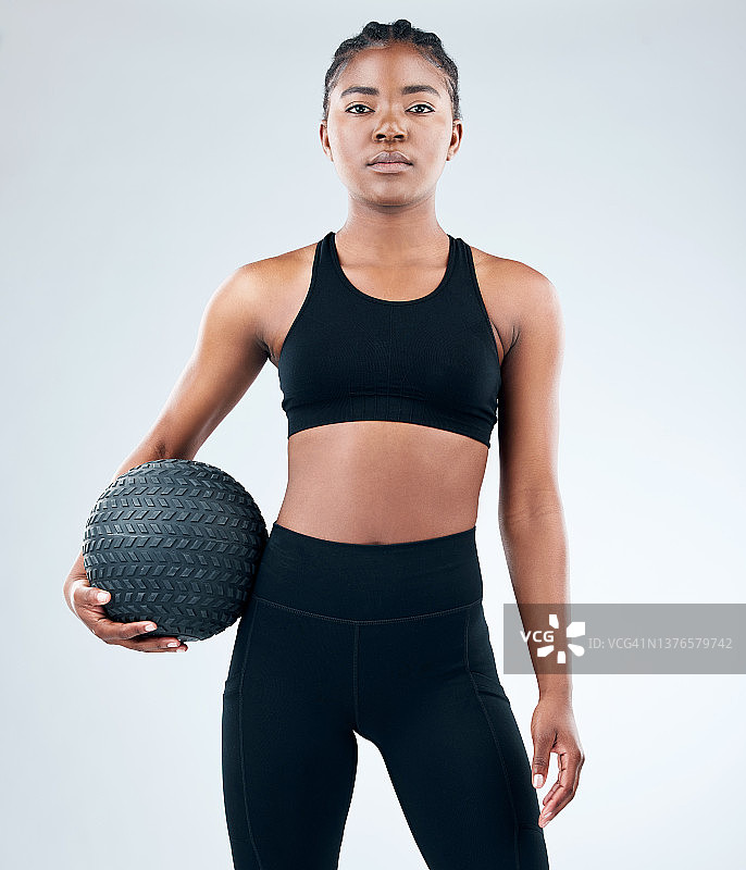 这张照片是一个运动的年轻女子在工作室背景下与一个实心球摆姿势图片素材