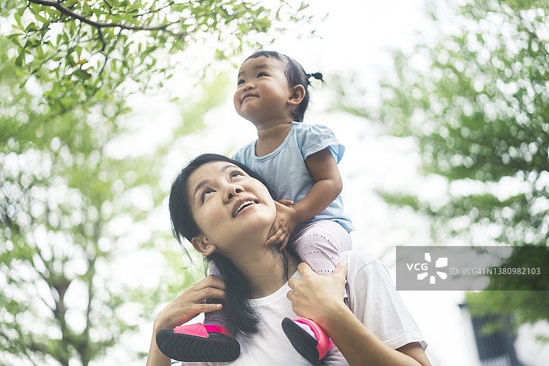 积极情绪亚洲母亲背女儿休闲户外公共花园周末活动图片素材