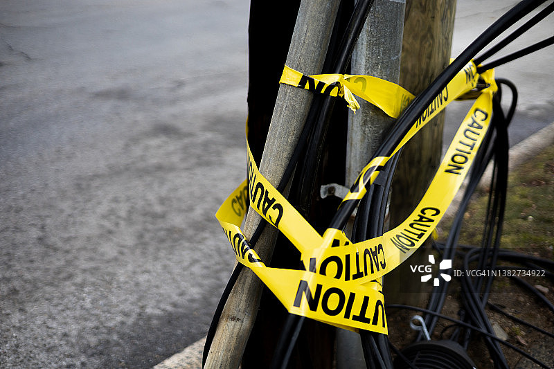 警告:黄色的警告胶带缠在街上倒下的电线上图片素材