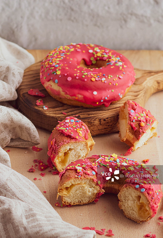 圆形的甜甜圈和粉红色的糖霜放在木板上。糖果的精美排列图片素材